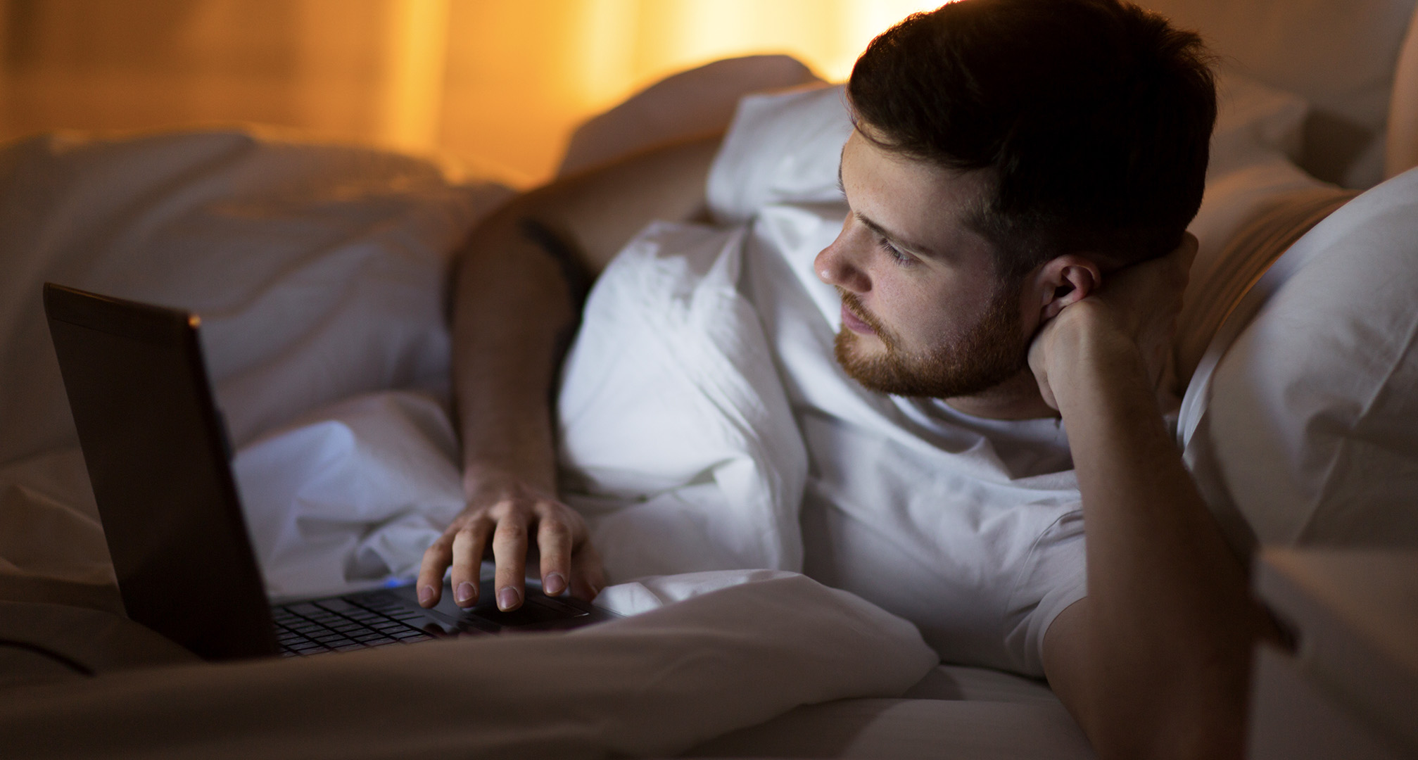 persona que utiliza el portátil desde la cama por la noche