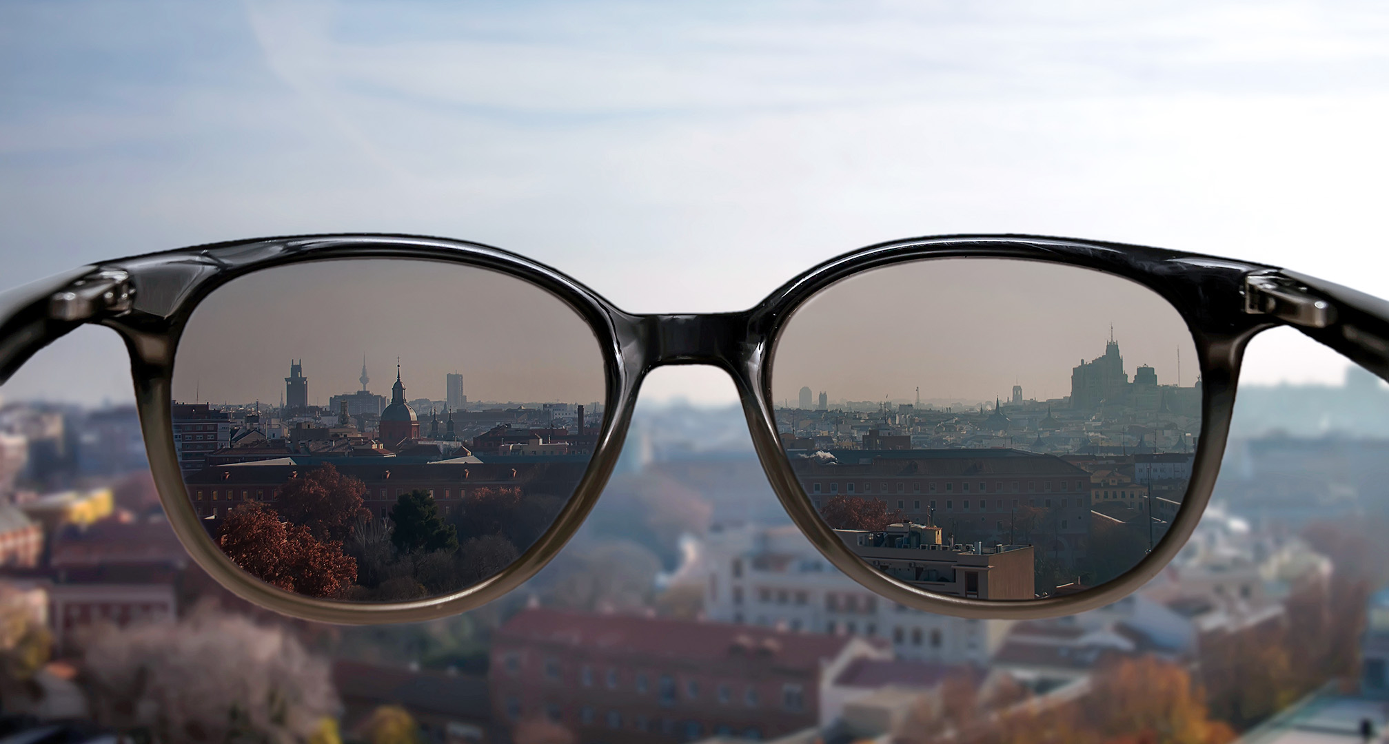 gafas de sol sostenidas frente a un paisaje urbano de fondo
