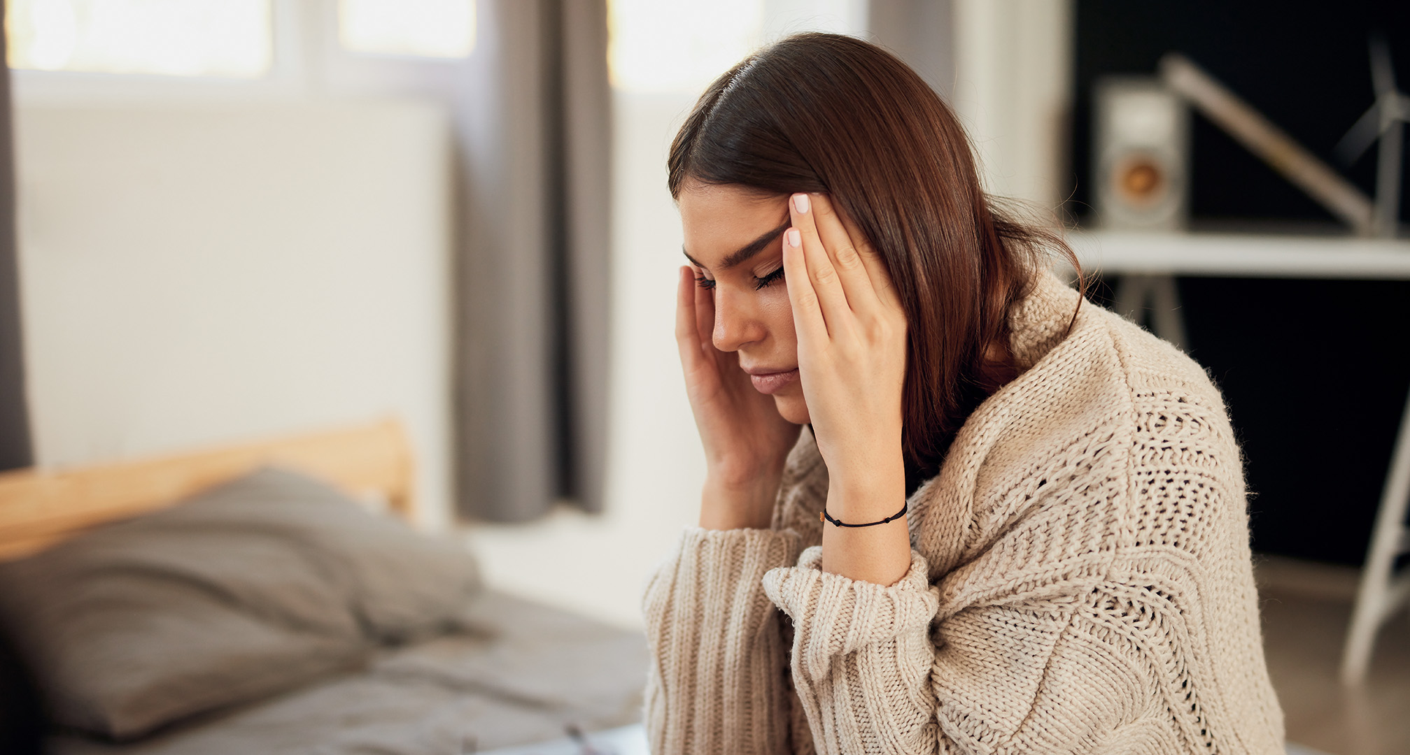 persona con los ojos cerrados sujetándose la cabeza